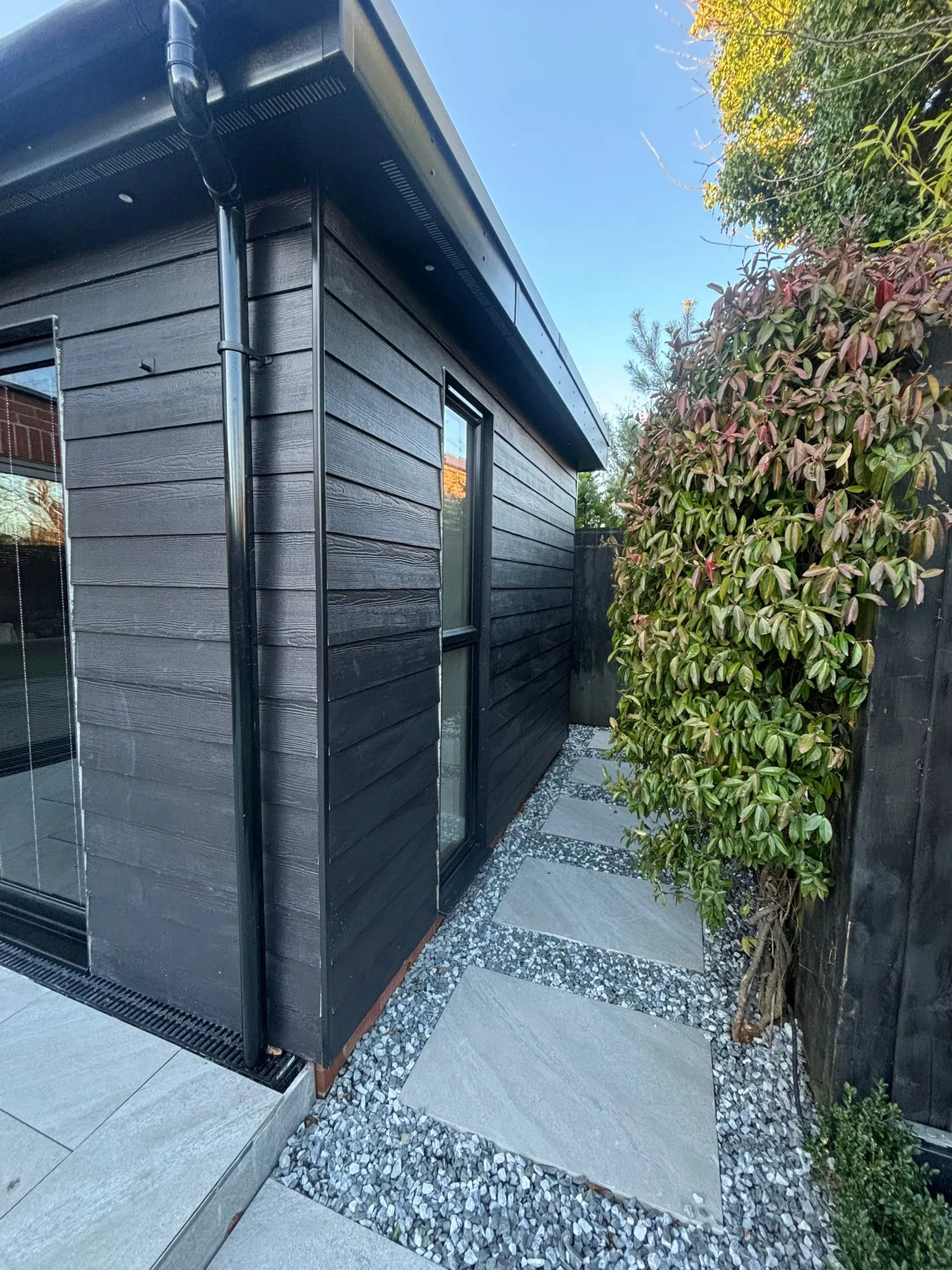 Composite clad garden room extension with a stepping stone path in Essex