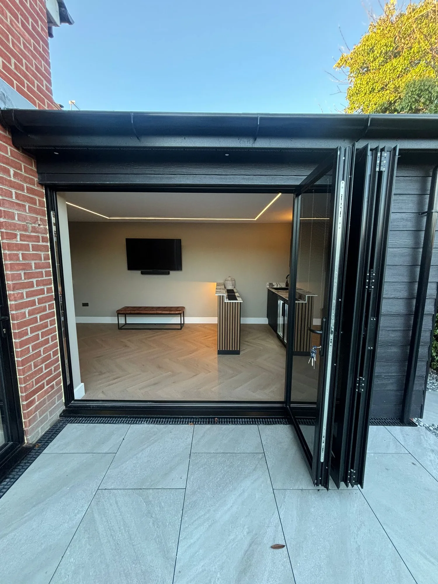 Open bifold doors into a finished extension lounge in Essex