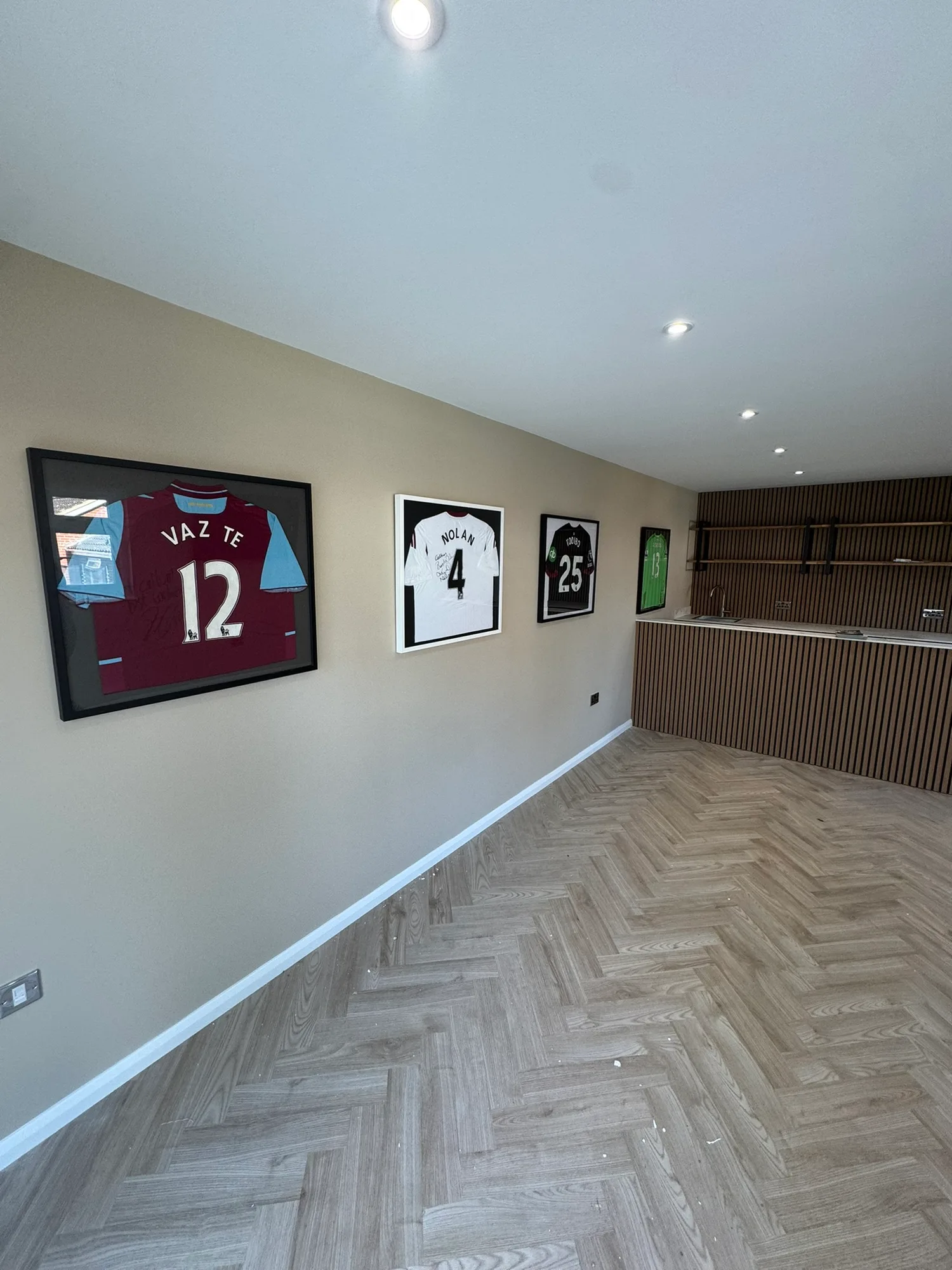 Fitted garden room interior with kitchenette and wood-slat wall in Essex