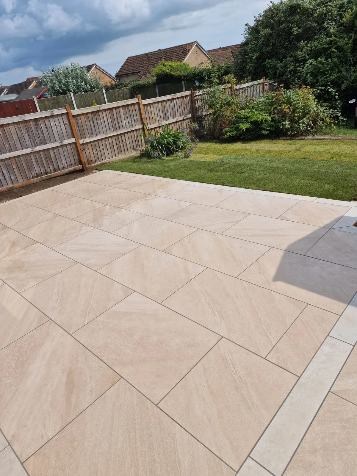 Beige porcelain paving with a grey border and lawn in an Essex garden