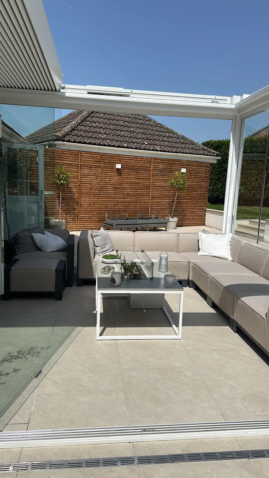 Porcelain patio and glass garden room with cedar screen fencing in Essex