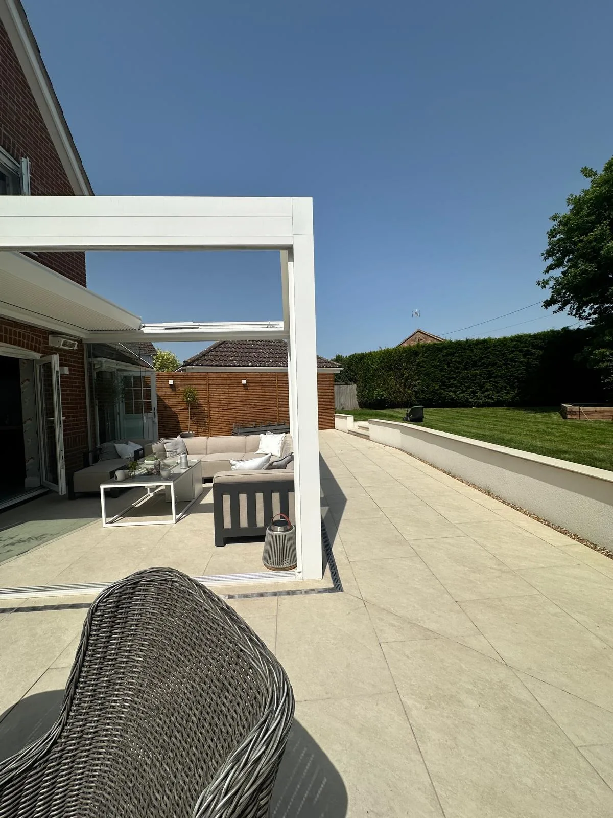 Cream porcelain patio with a white veranda and gravel border in an Essex garden