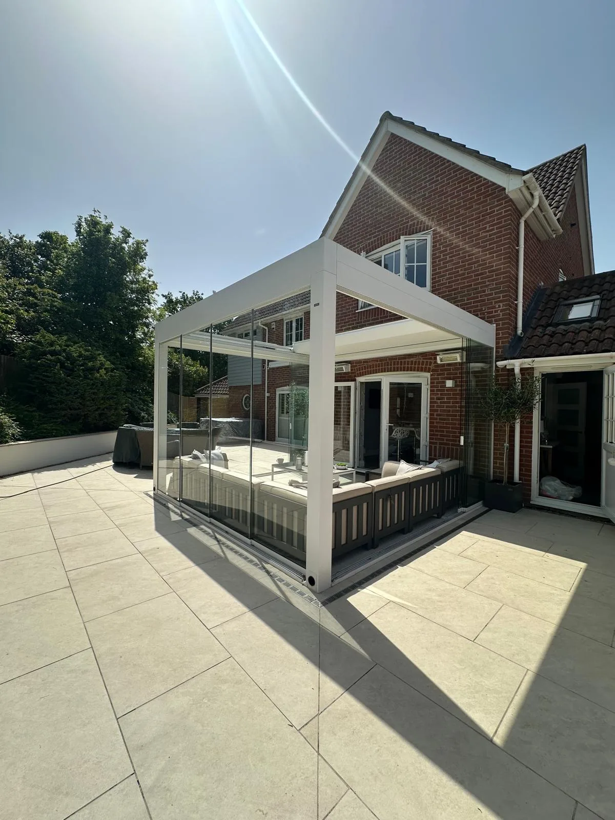 Cream porcelain terrace with a glass veranda beside a brick house in Essex