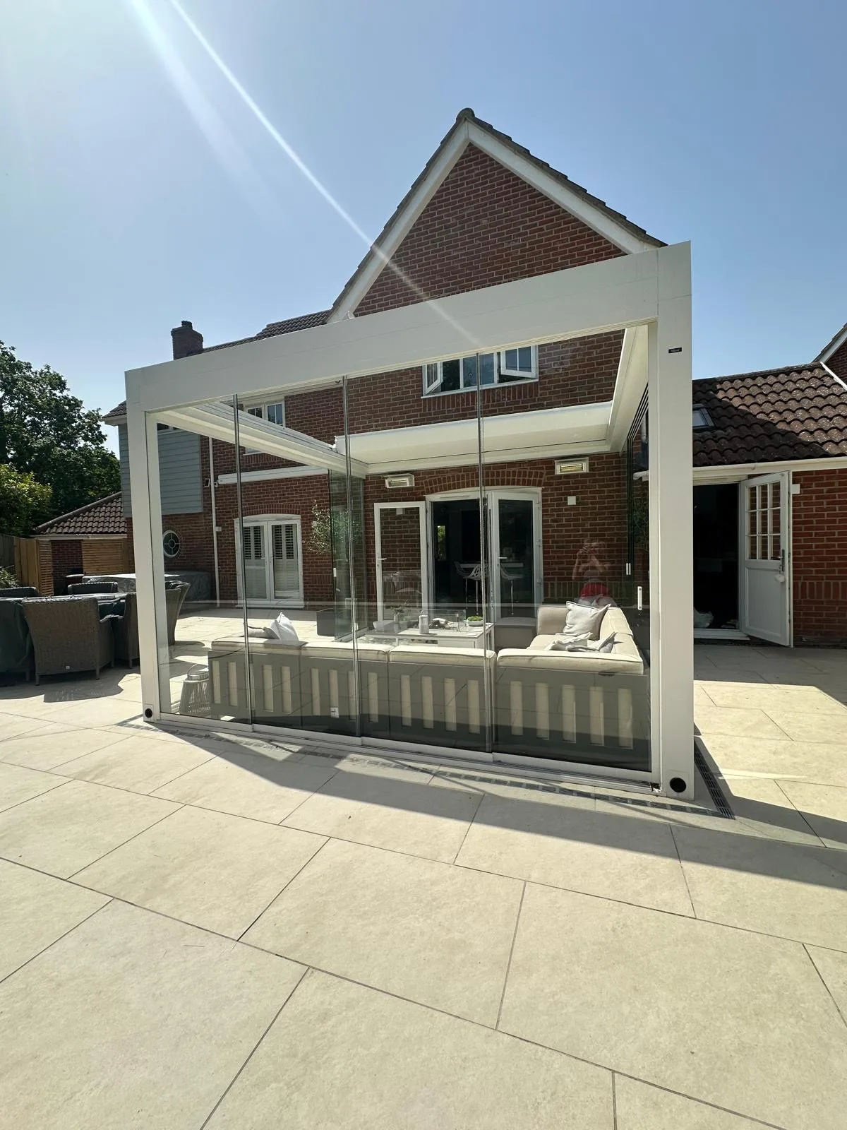 Cream porcelain patio with a glass garden room at an Essex property
